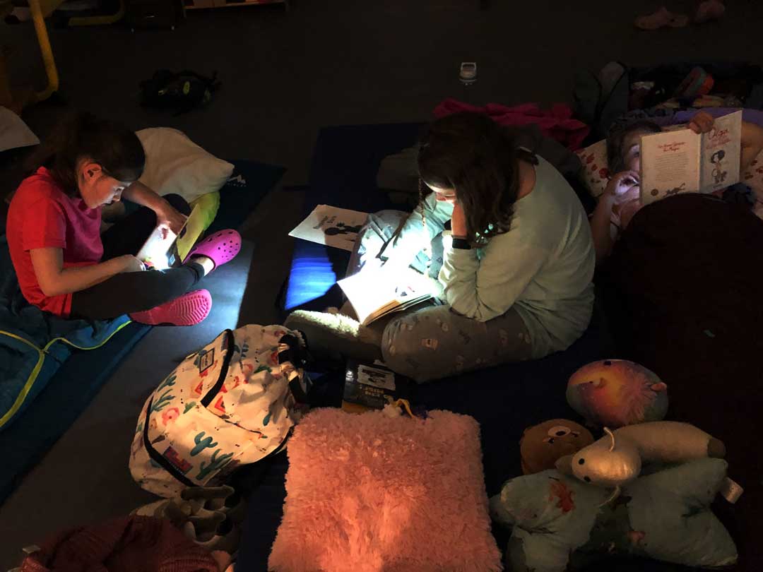 Kinder lesen mit Taschenlampen bei der Lesenacht der FES Grundschule.